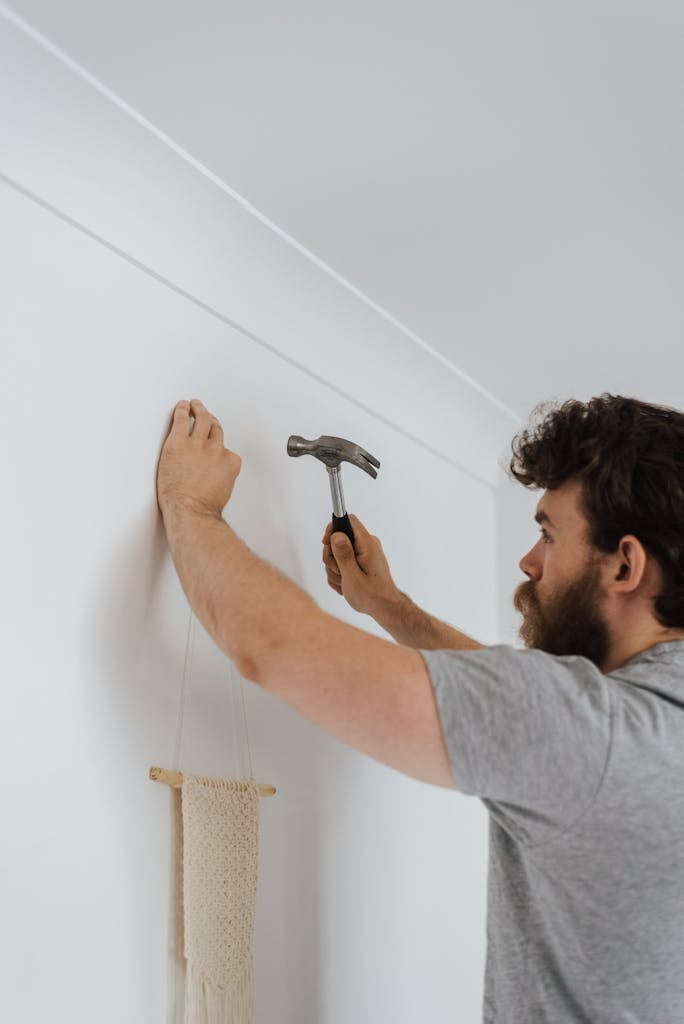 Man hammering nail into wall during housework